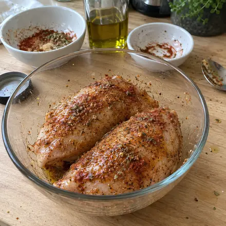 Rohe Hähnchenbrust in einer Glasschüssel, mit Öl und Gewürzmischung eingerieben