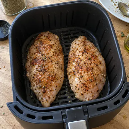 Zwei gewürzte, rohe Hähnchenbrustfilets nebeneinander im Airfryer-Korb