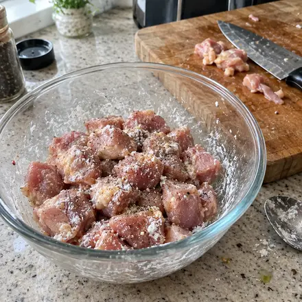 Rohe Hähnchenwürfel in einer Glasschüssel, mit Speisestärke bestäubt